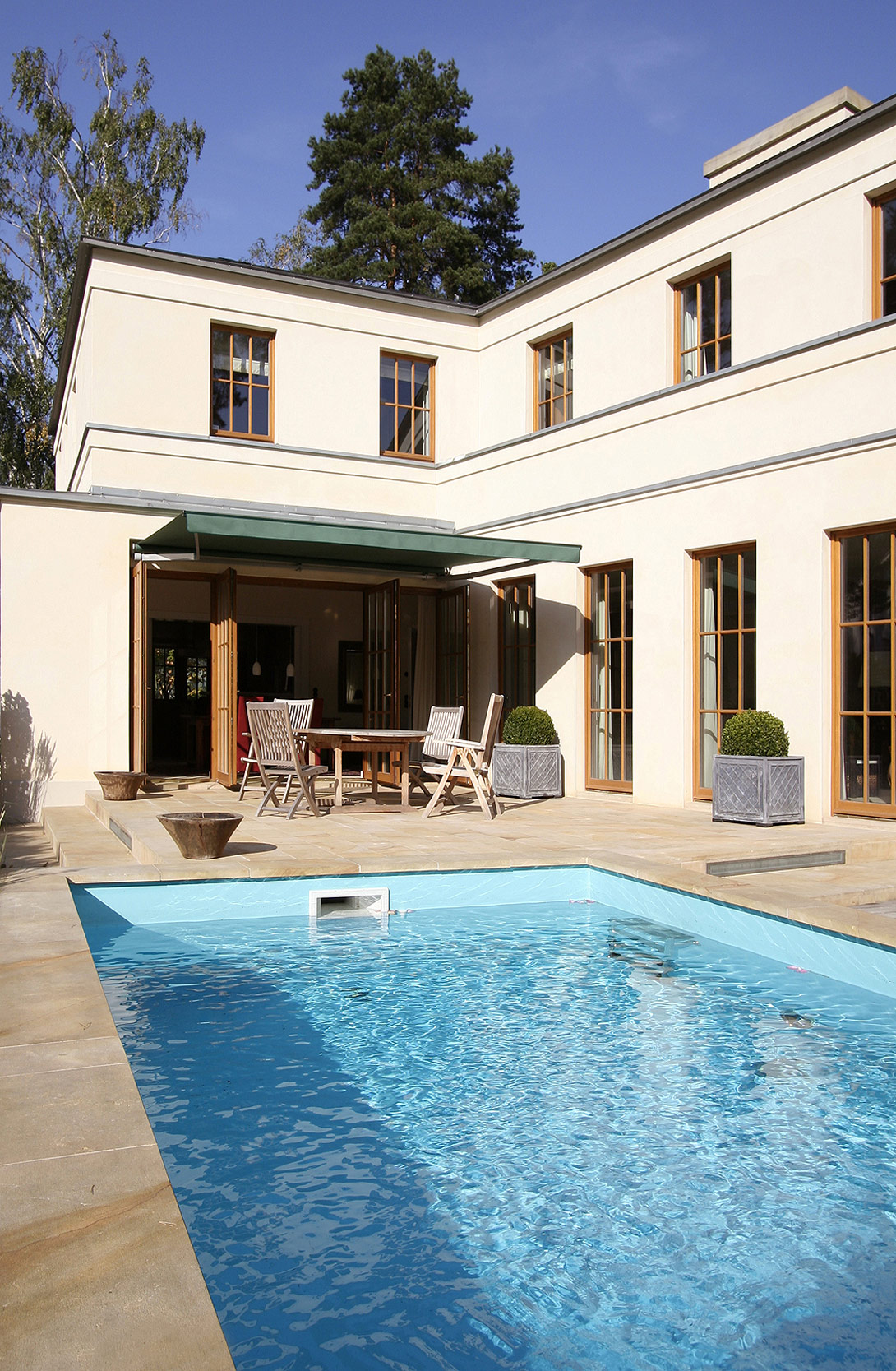 Die Terrasse vor dem Esszimmer besitzt einen beiheizten Außenpool. ENGLISH-INSPIRED – Domizil mit Landhausflair – Neubau einer Villa im englischen Landhausstil - Die Terrasse vor dem Esszimmer mit Außenpool