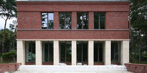 Die Gartenansicht ist mit Travertinsockel und einer Lochfassade aus Backstein.